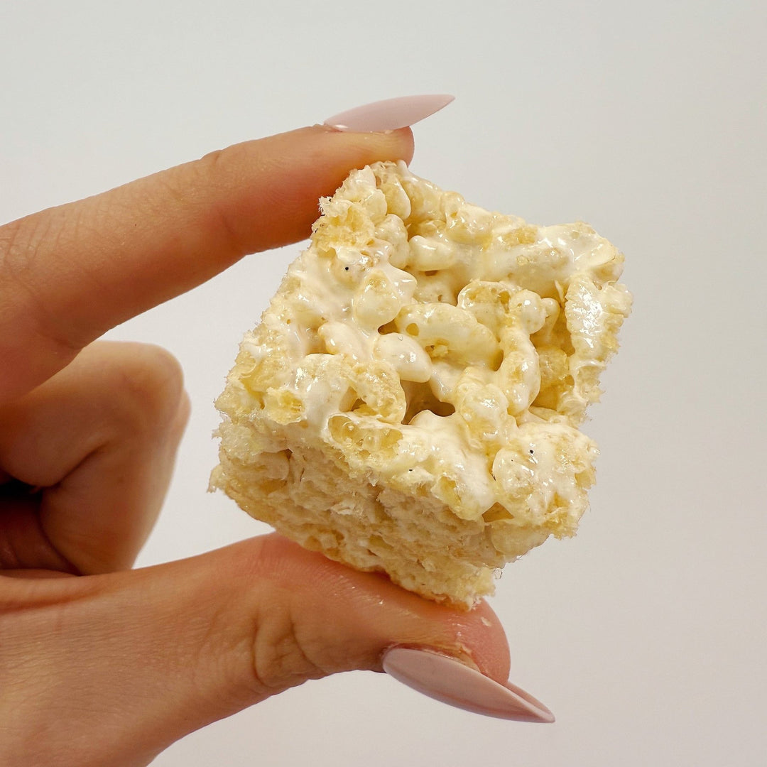 Hand holding a gluten free bite sized rice crispy treat from XO Marshmallow against a plain background