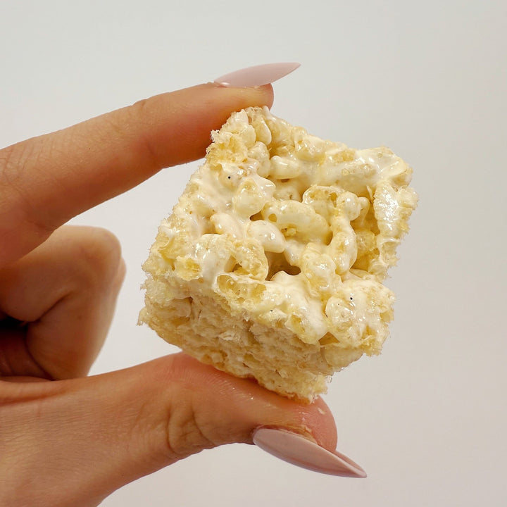 Hand holding a gluten free bite sized rice crispy treat from XO Marshmallow against a plain background