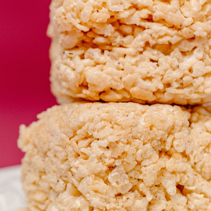 A stack of gluten free bite sized rice crispy treats from XO Marshmallow against a red/deep pink background