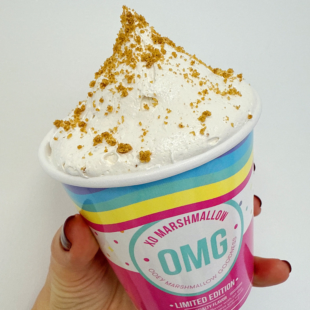 Hand holding cookie butter marshmallow creme against a white background