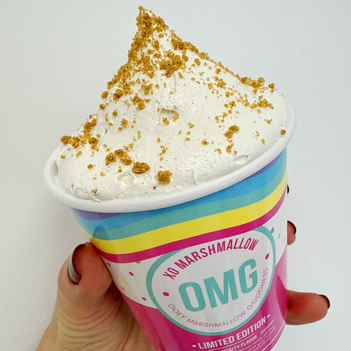 Hand holding cookie butter marshmallow creme against a white background