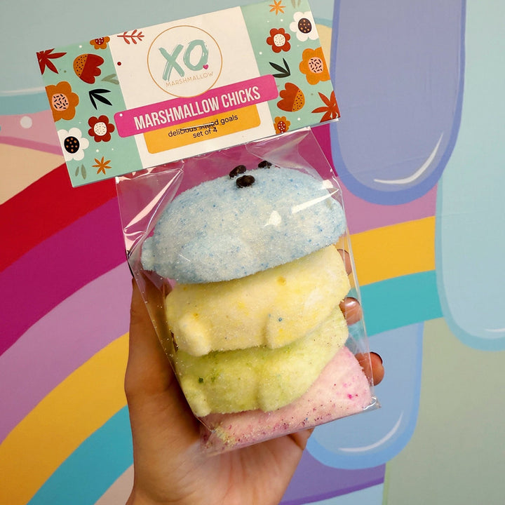 Packaged marshmallow chicks with a colorful label against a multicolored background
