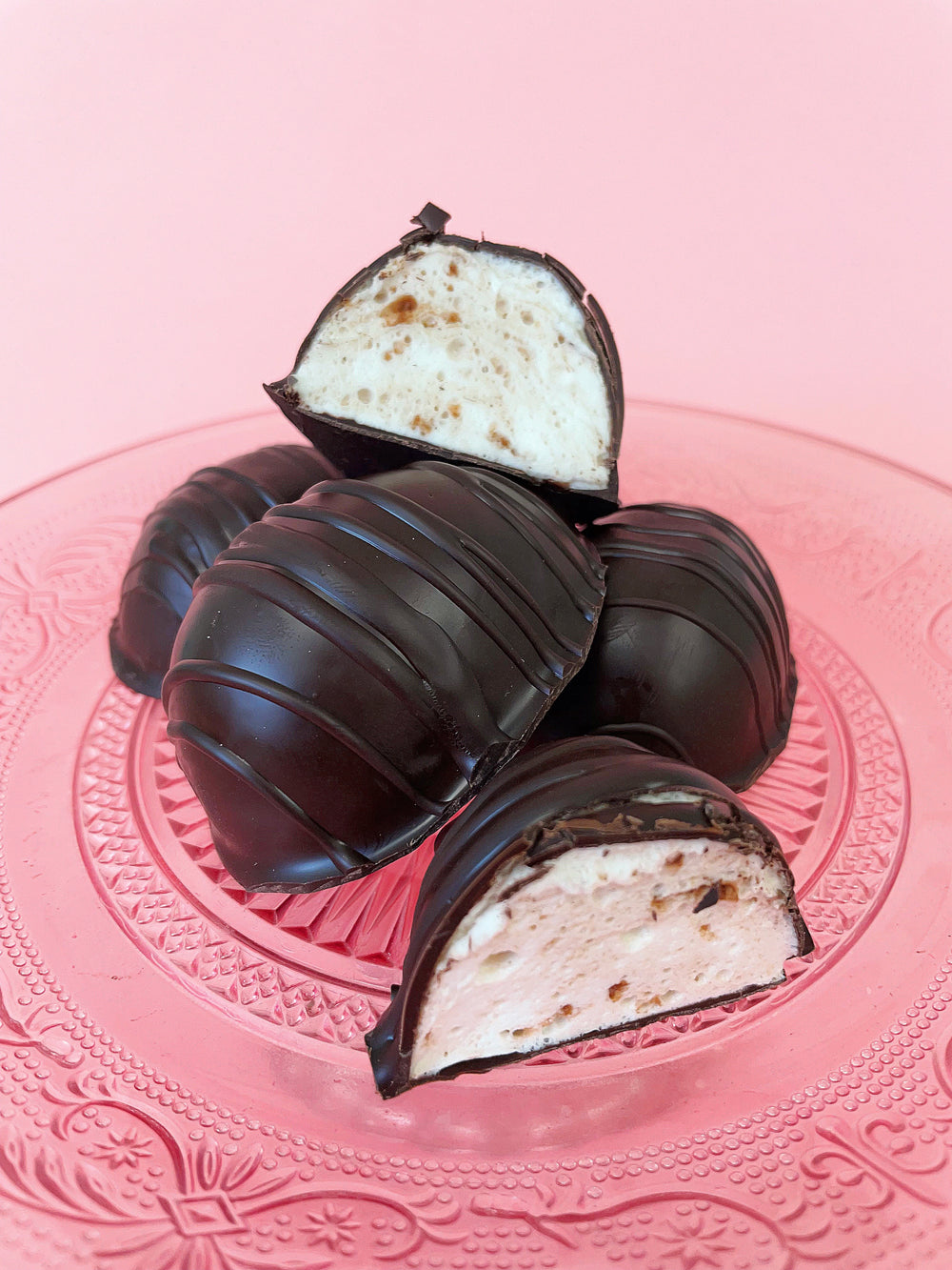 A pile of chocolate covered eggs with a nutella marshmallow center on a pink glass plate