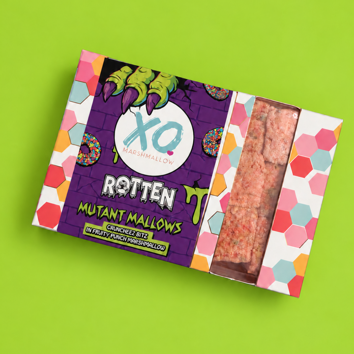 A box of XO Marshmallows Rotten Mutant Marshmallows, featuring a purple and multicolor Halloween-themed label with a clear window showing the pinkish-brown marshmallows inside, set against a bright lime green background.