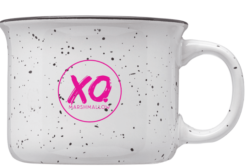 A simple mockup of the XO Marshmallow ceramic campfire mug. It's a white mug with black speckles and has the XO Marshmallow circle logo on it in hot pink.