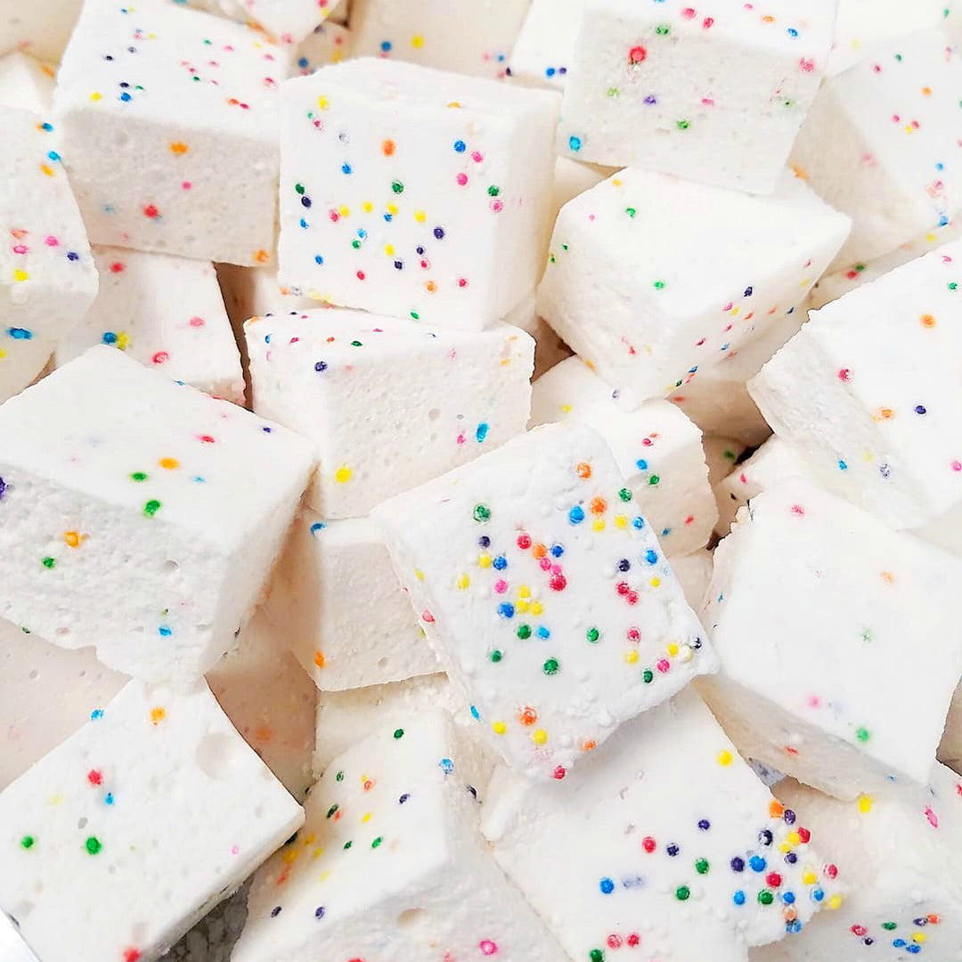 A close-up image of funfetti birthday cake marshmallows with multicolored sprinkles on them.