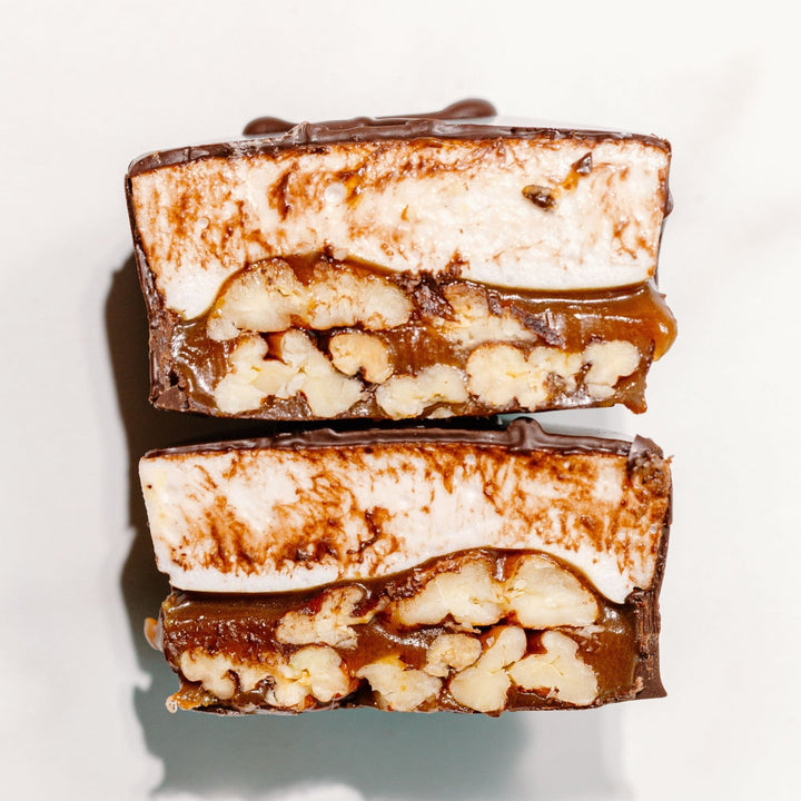 A cross section of a marshmallow turtle candy against a white background. It shows caramel, pecans and vanilla homemade marshmallow 