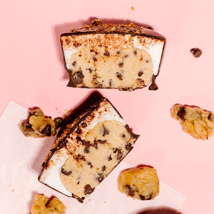 A cross section of XO Marshmallow's Oh Dough You Didn't Cookie Dough cups showing that the inside is filled with layers of chocolate chip cookie dough and marshmallow and the entire outside is coated in chocolate